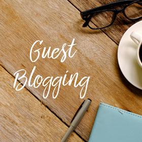 A table with a coffee cup, glasses, notebook, pen, and the words "guest blogging"