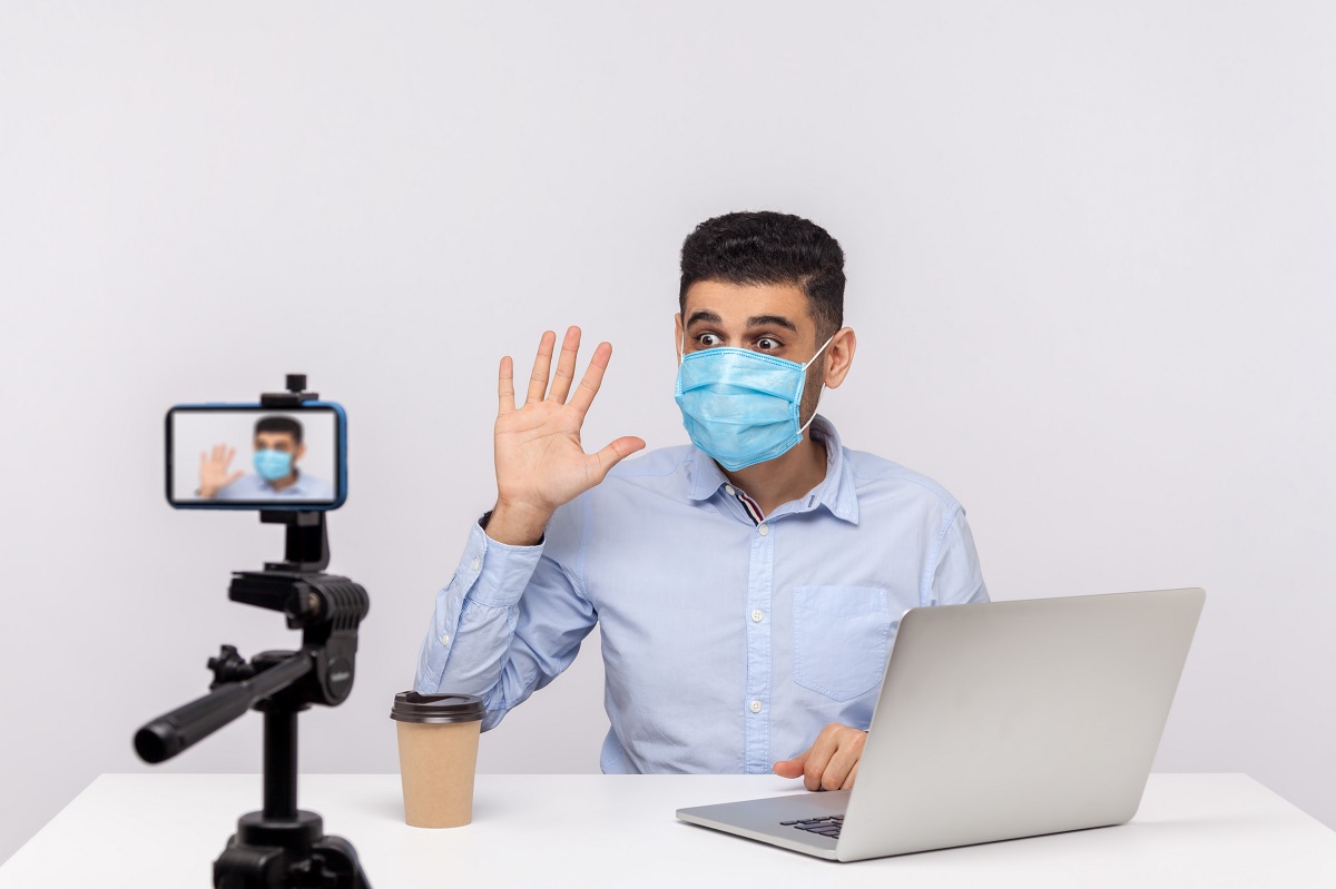 Male blogger in medical mask making video, online streaming about coronavirus news, giving tips on using protect filter against contagious disease. indoor studio shot isolated on white background