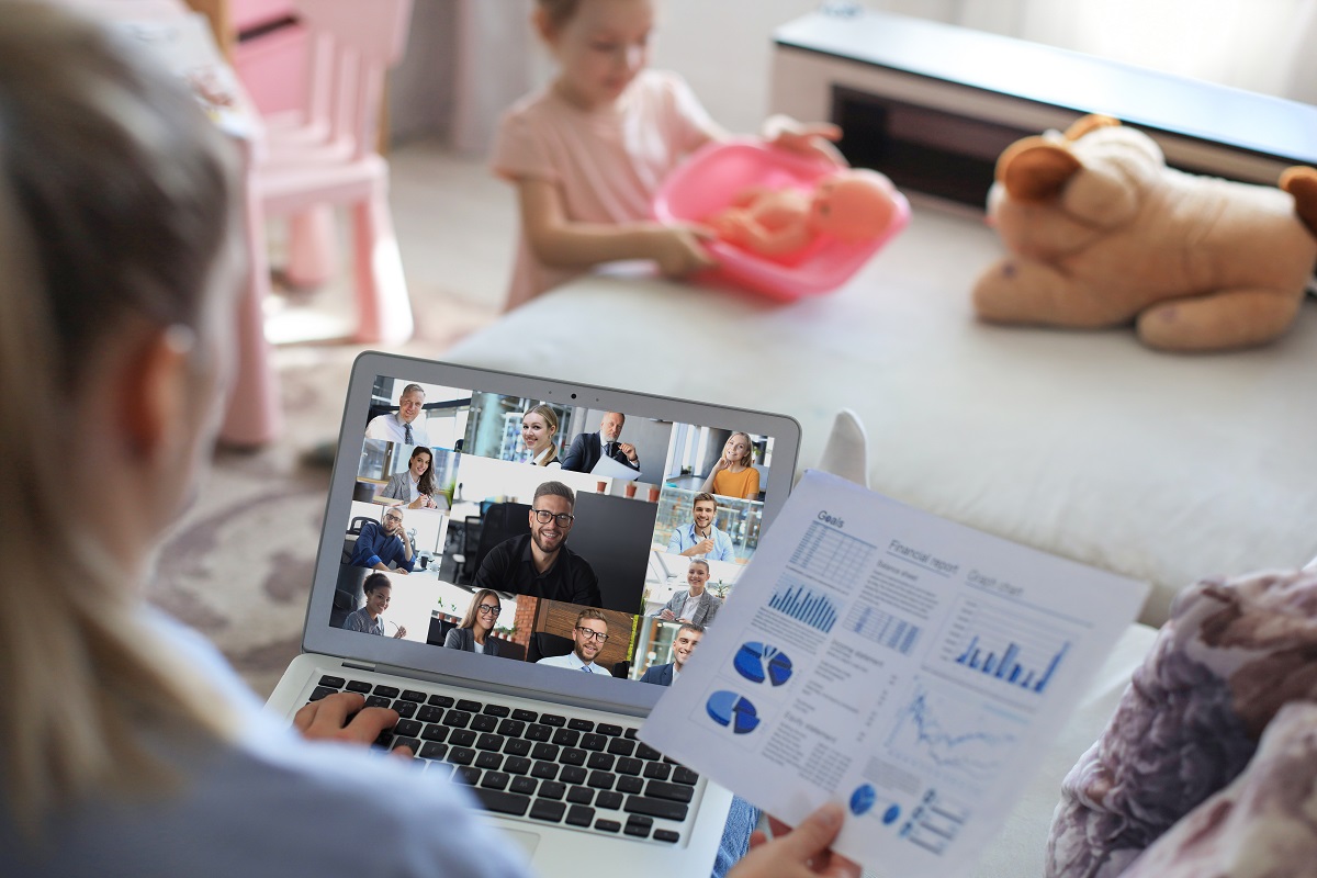 Young woman works from home with child at the background during self isolation and quarantine. Work online and stay at home. Coronavirus outbreak, flu epidemic and covid-19