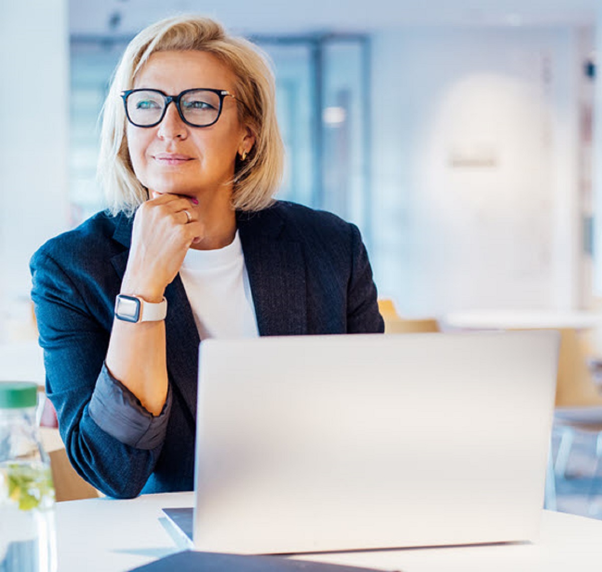 Woman at laptop thinking while looking off in the distance